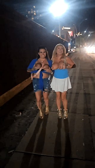 Two girls walking down the street with their boobs out'